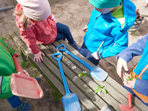 Kinder legen Schaufeln auf die Holzbank