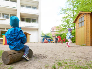 Ein Kind sitzt auf einem Holzblock
