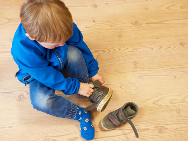 Kind zieht sich selbstständig die Schuhe an
